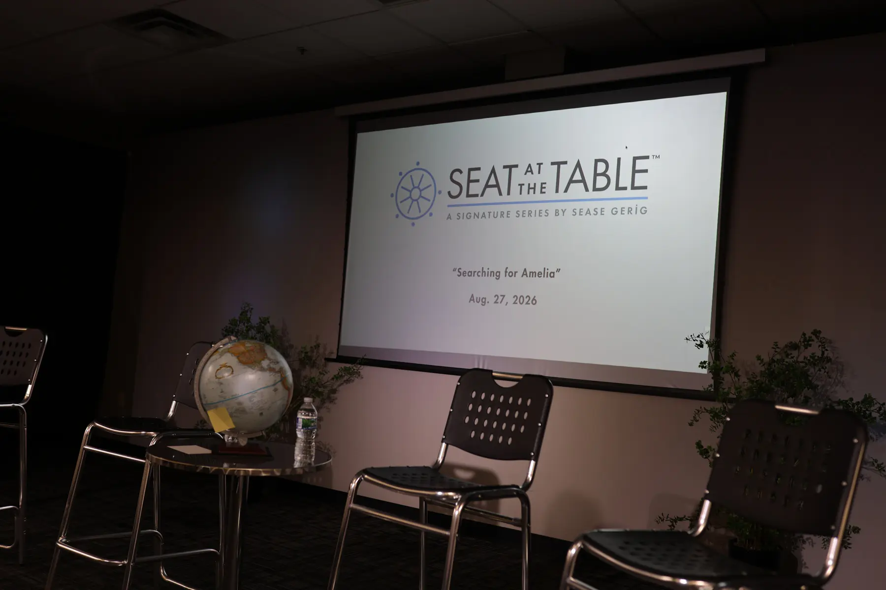The stage before guests arrived, the Seat at the Table title on screen and a globe on the side table