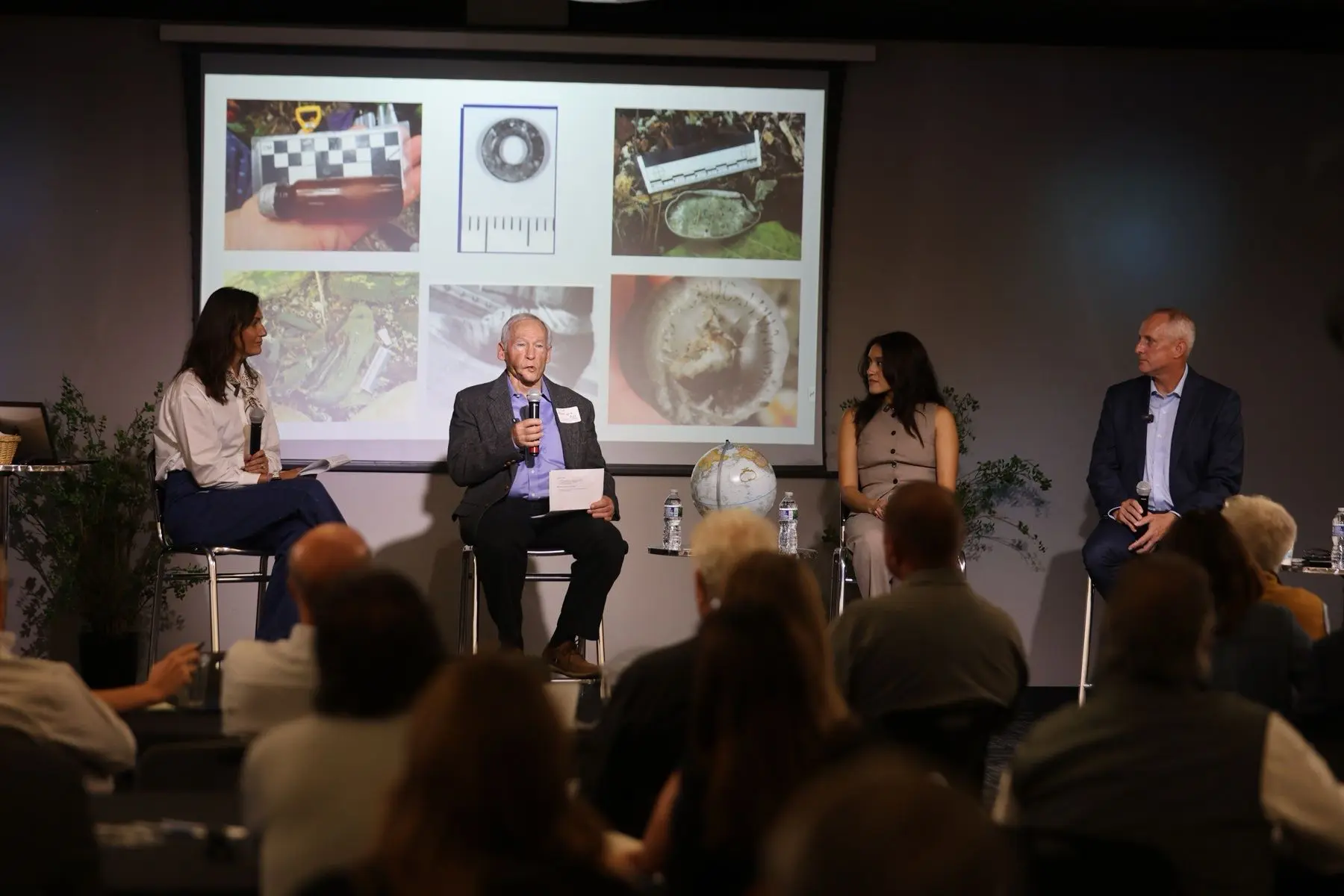 The panel mid-conversation, photos of expedition finds on the screen behind them